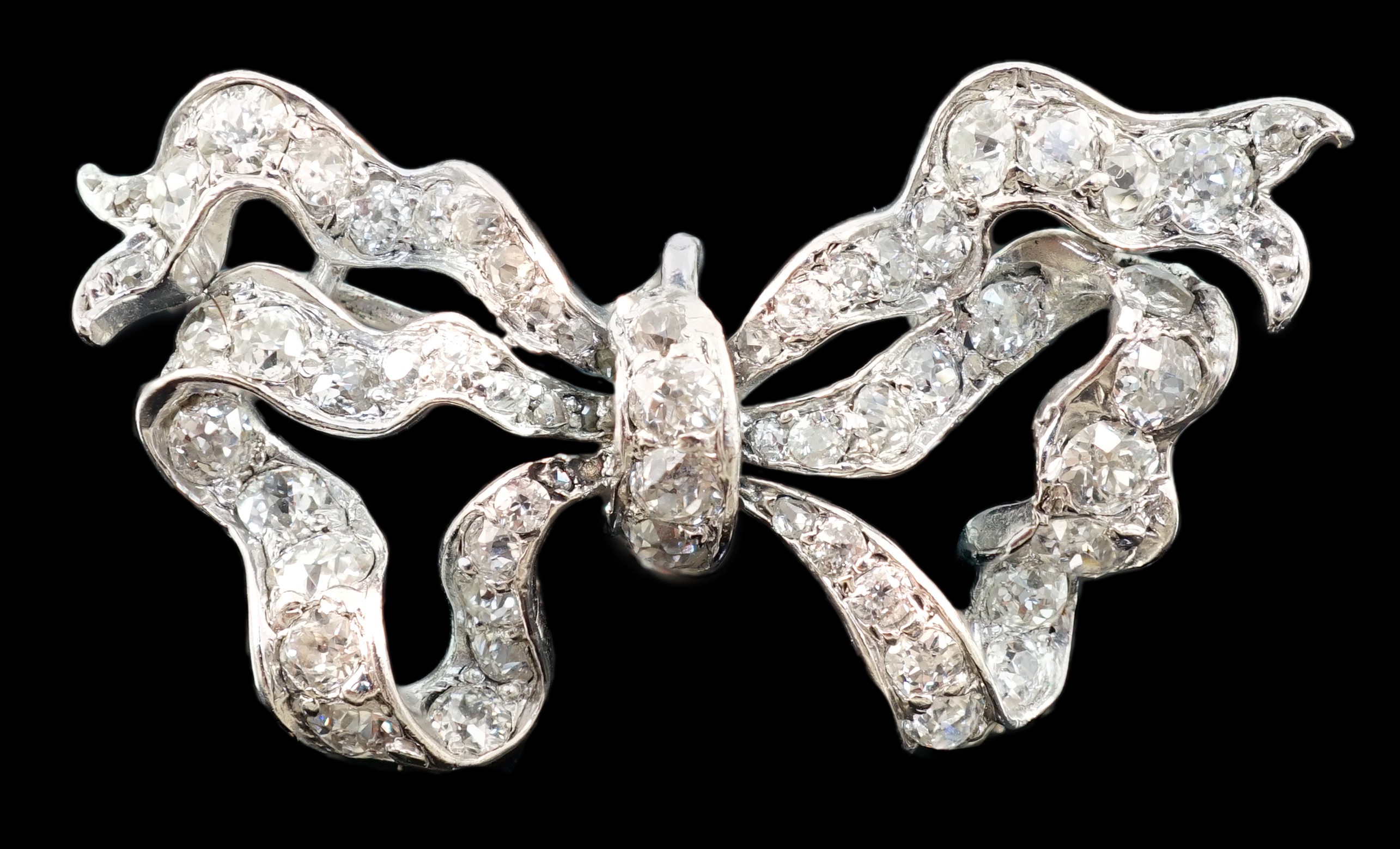 An early to mid 20th century platinum and diamond cluster set ribbon bow pendant brooch